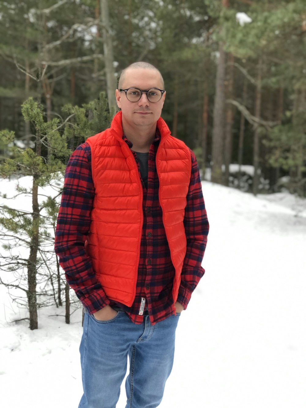 a man standing in the snow wearing a red vest