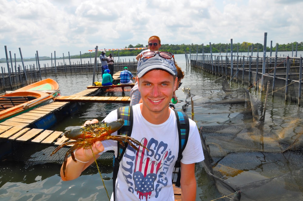 a man holding a crab in front of a dock