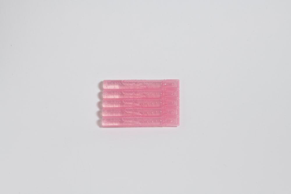 three pink toothbrushes on a white surface