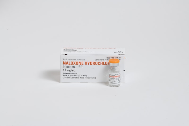 A box and vial of naloxone hydrochloride injection on a white surface