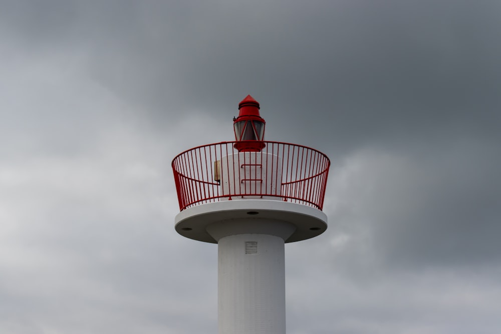 a red and white lighthouse on a cloudy day