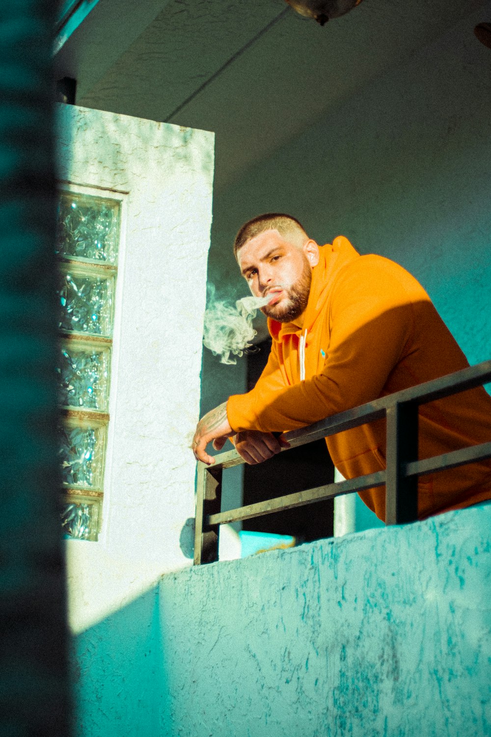 a man in an orange jacket leaning on a railing