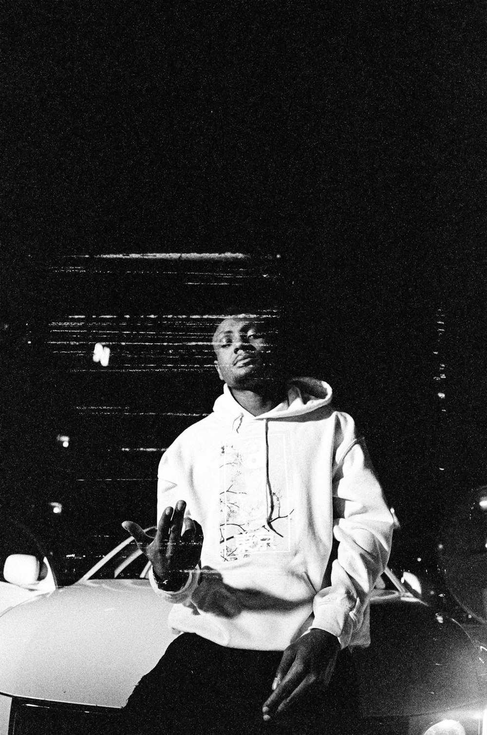 a black and white photo of a man sitting on a car