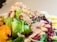 A vibrant salad features fresh lettuce, arugula, radicchio, white beans, shredded chicken, sliced boiled eggs, and ripe tomato slices. The ingredients are seasoned with black pepper, adding texture and contrast to the colorful array of greens, purples, and yellows.