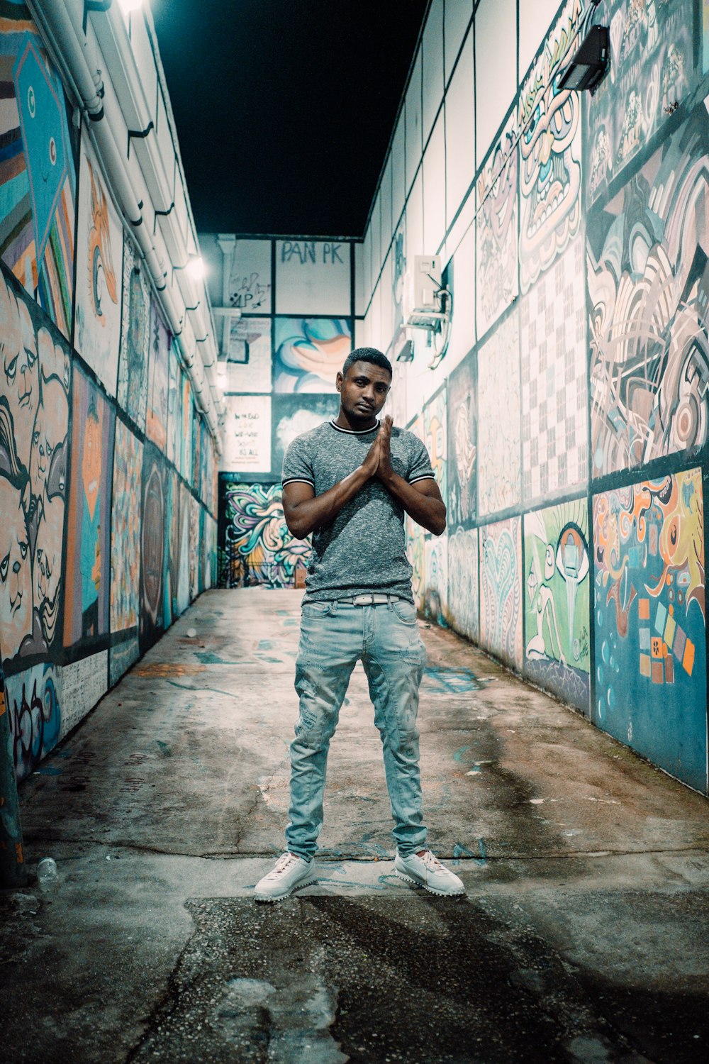 a man standing in an alley with graffiti on the walls