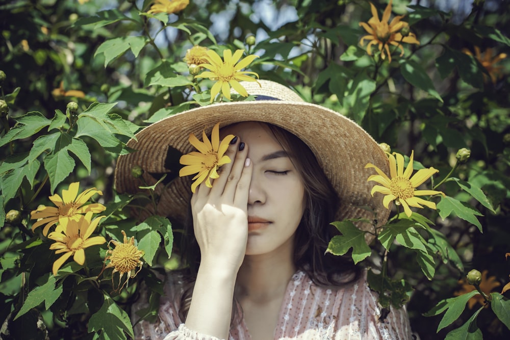 a woman wearing a hat and holding her hands to her face