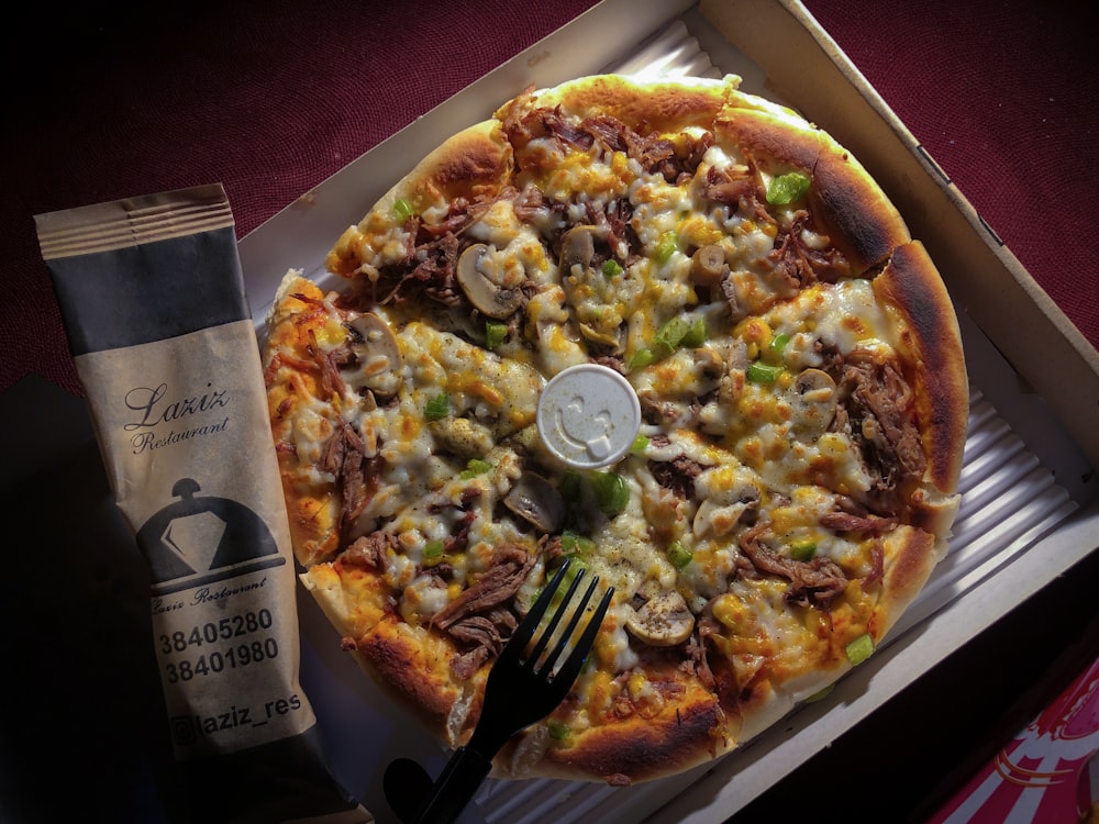 a pizza in a box with a fork and knife