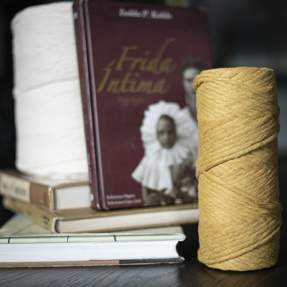 a stack of books sitting next to a spool of yarn