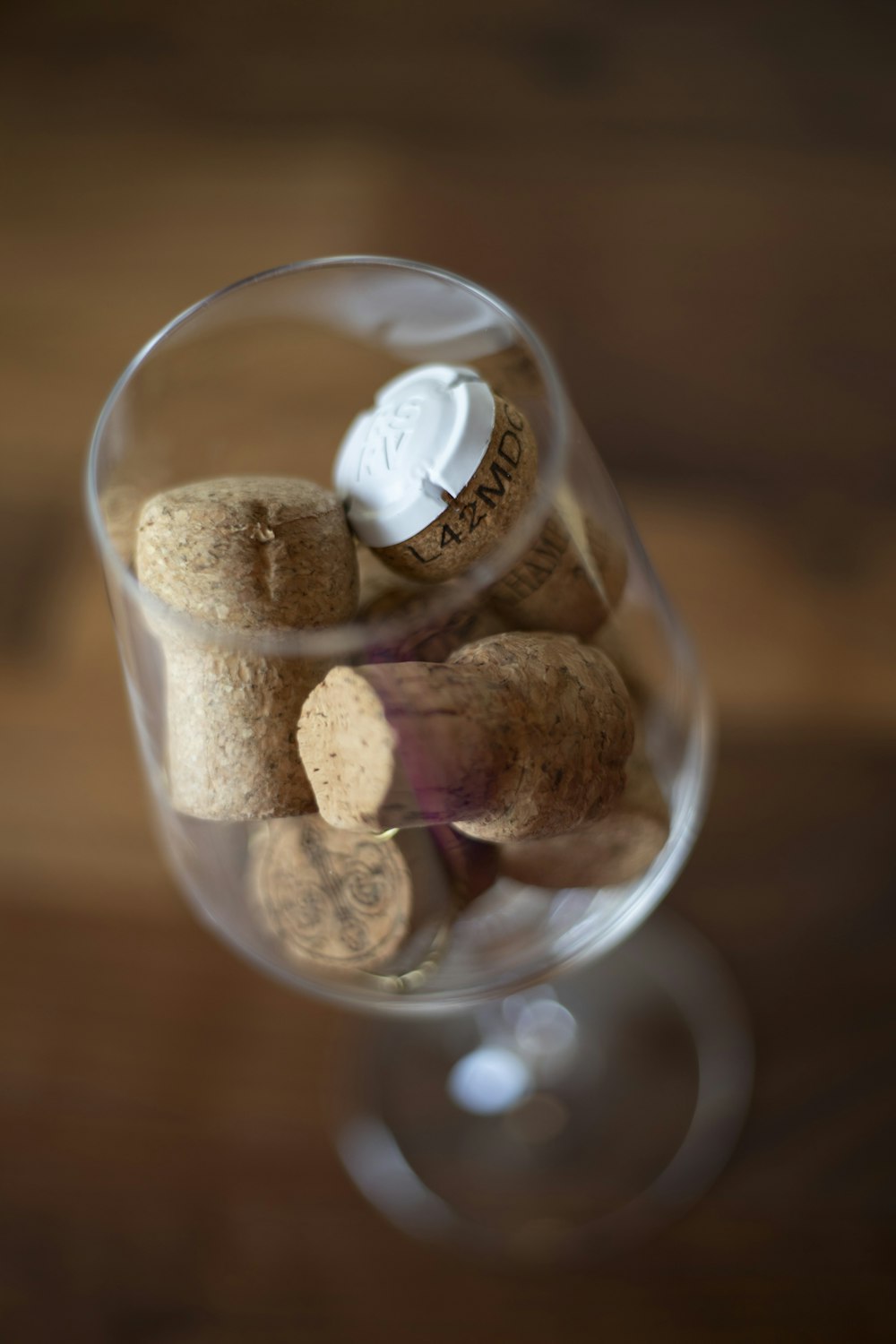 a glass filled with wine corks on top of a wooden table