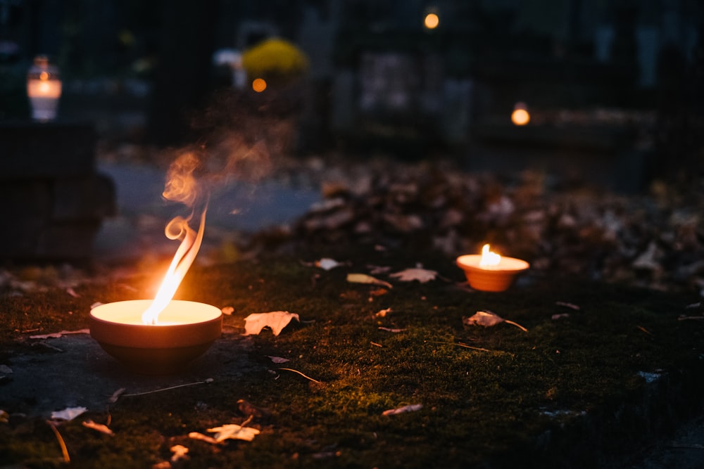 a bowl with a candle inside of it on the ground