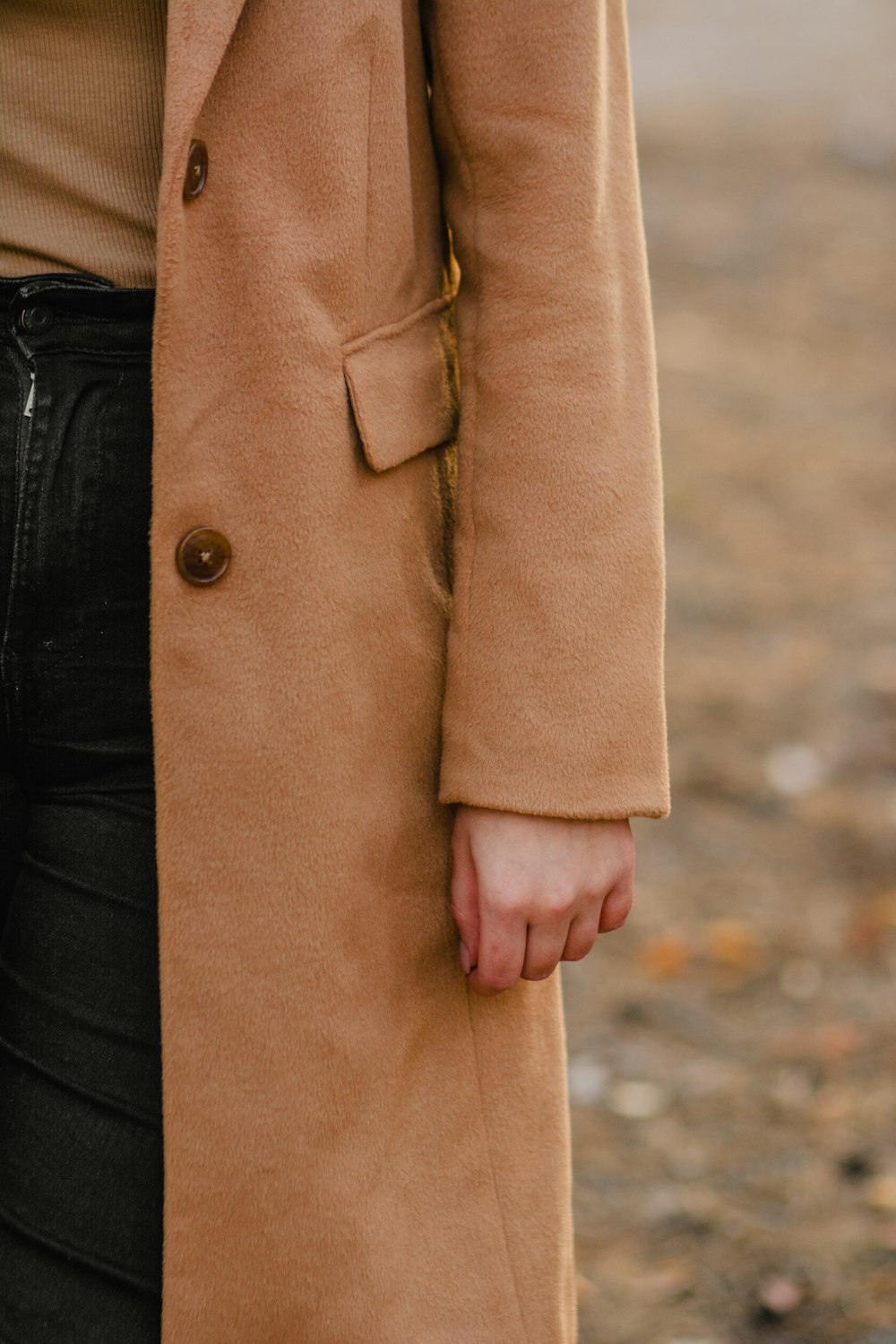 a woman wearing a tan coat and black jeans