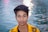 a boy with a yellow jacket standing in front of a body of water