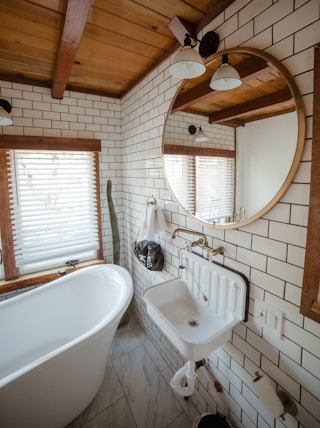 a white bath tub sitting under a bathroom mirror