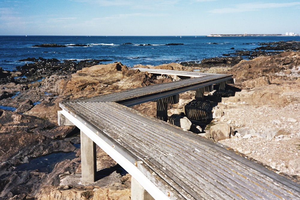 a wooden bench sitting on top of a rocky beach