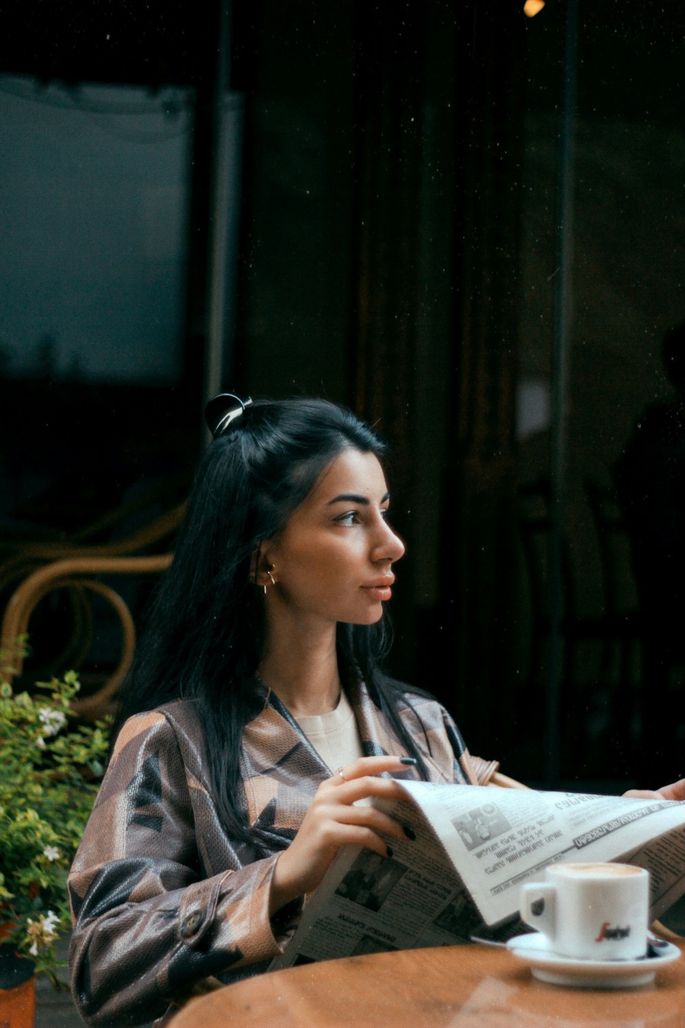 a woman sitting at a table reading a newspaper