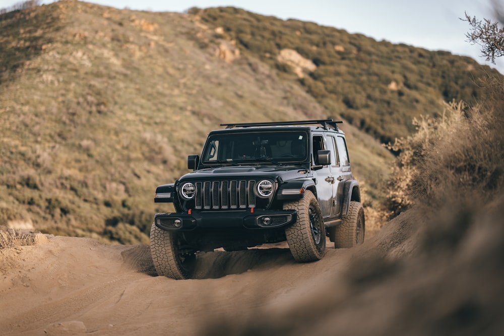 Ein schwarzer Jeep fährt eine unbefestigte Straße hinunter