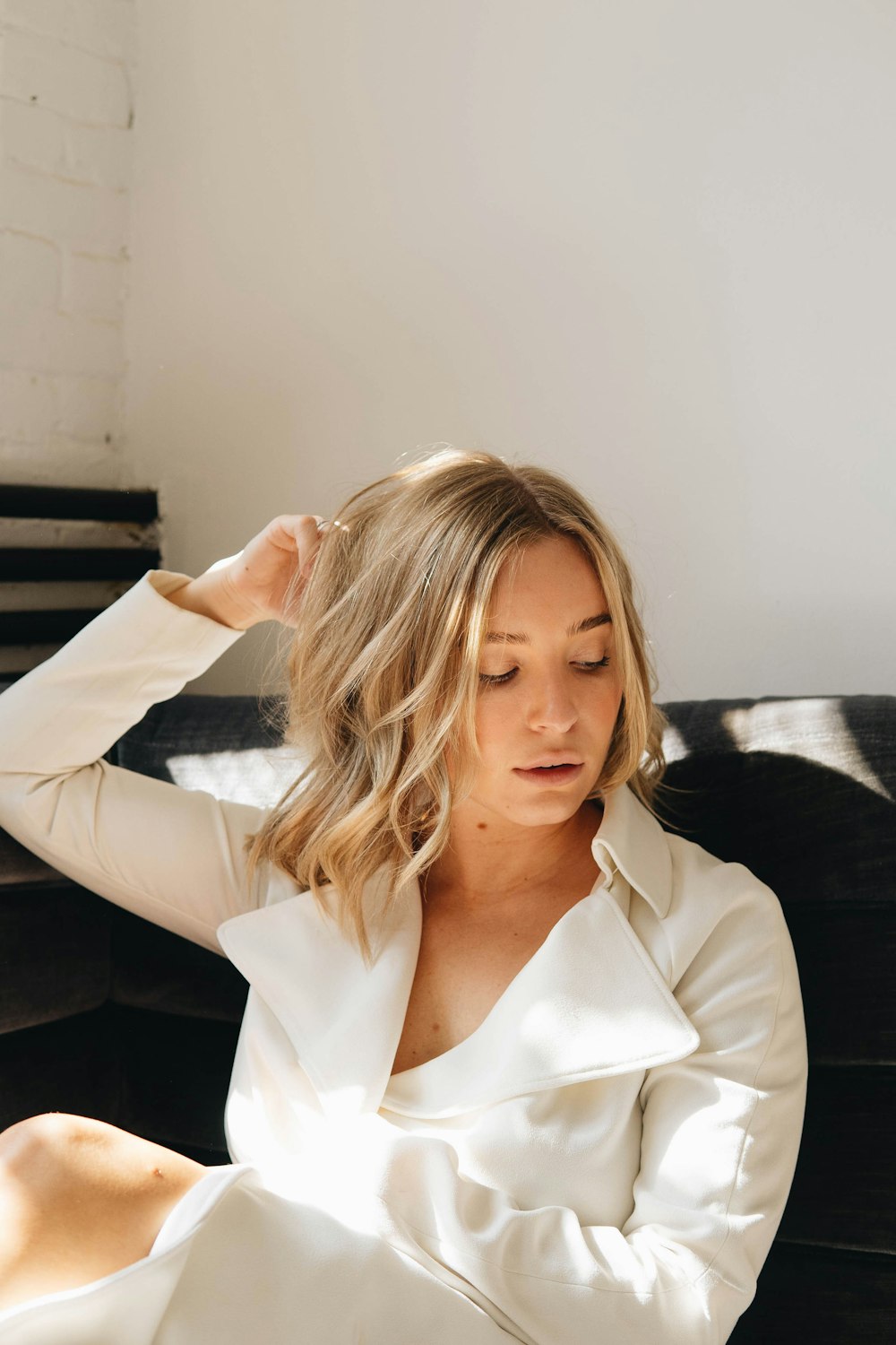 a woman sitting on a couch with her hands on her head