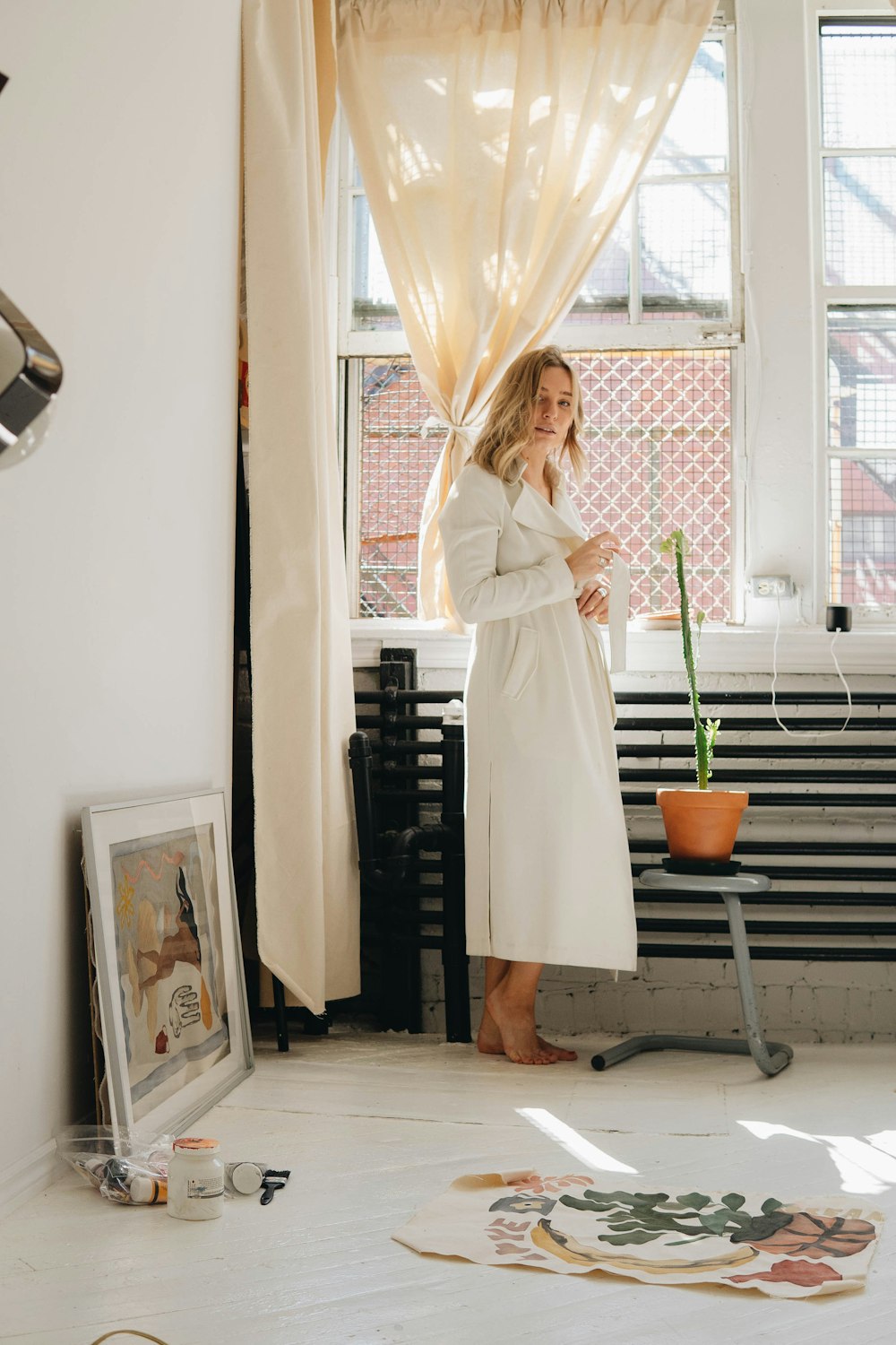 a woman in a bathrobe standing in front of a window