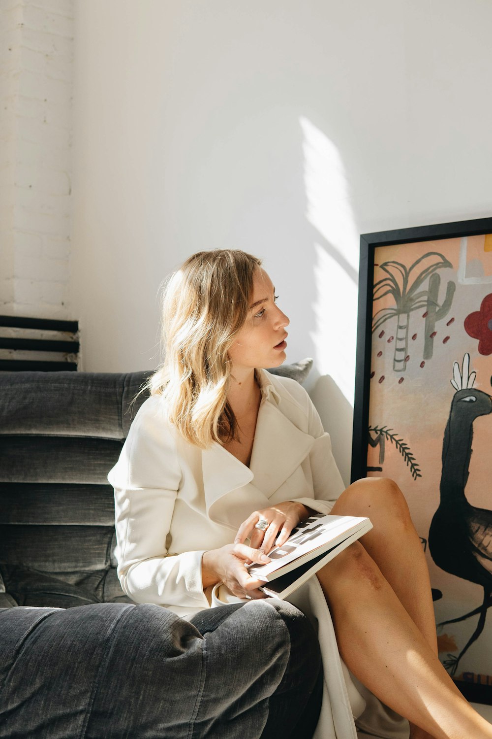 a woman sitting on a couch reading a book