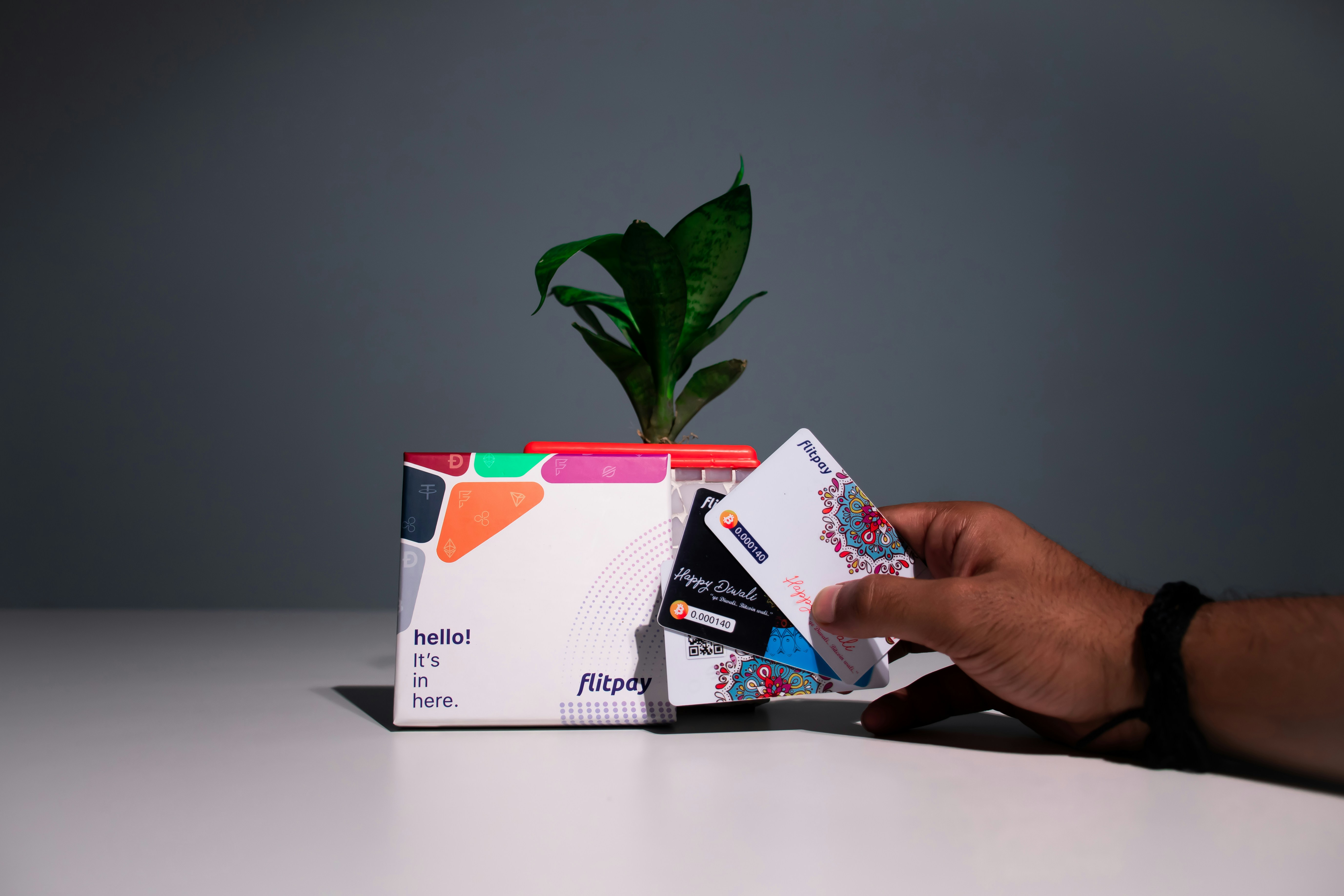 a hand holding a card next to a plant