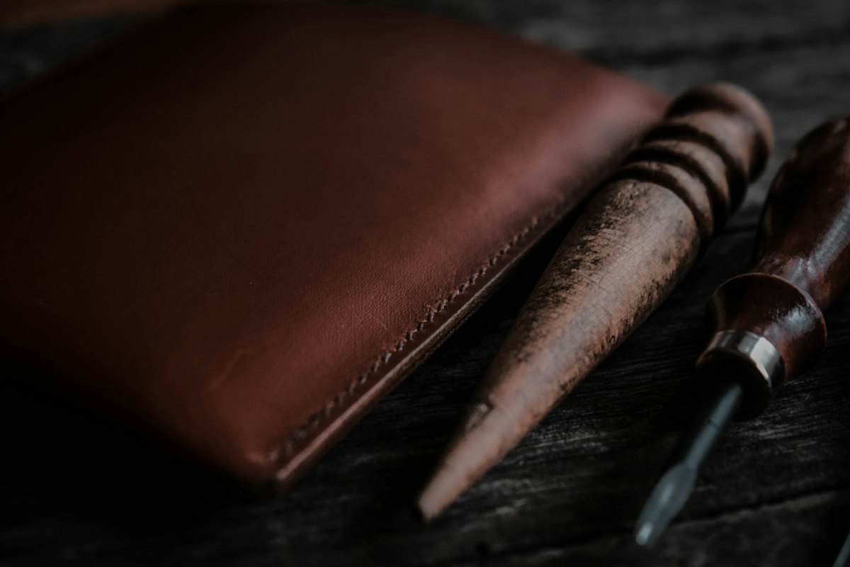 Un portefeuille en cuir cousu main et des outils de sellier en bois