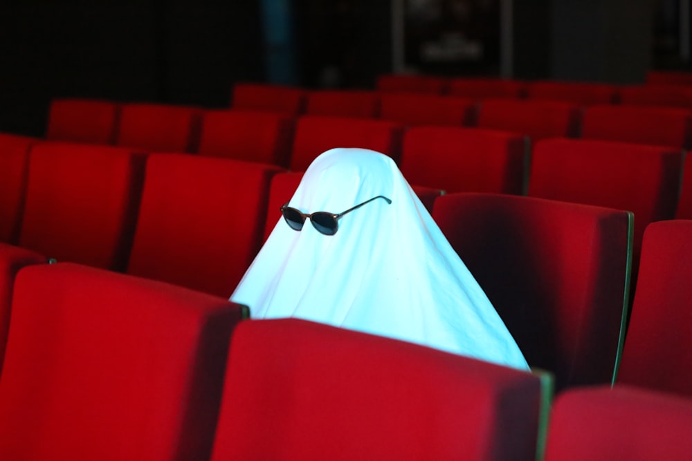 a ghost sitting in the middle of a row of red seats