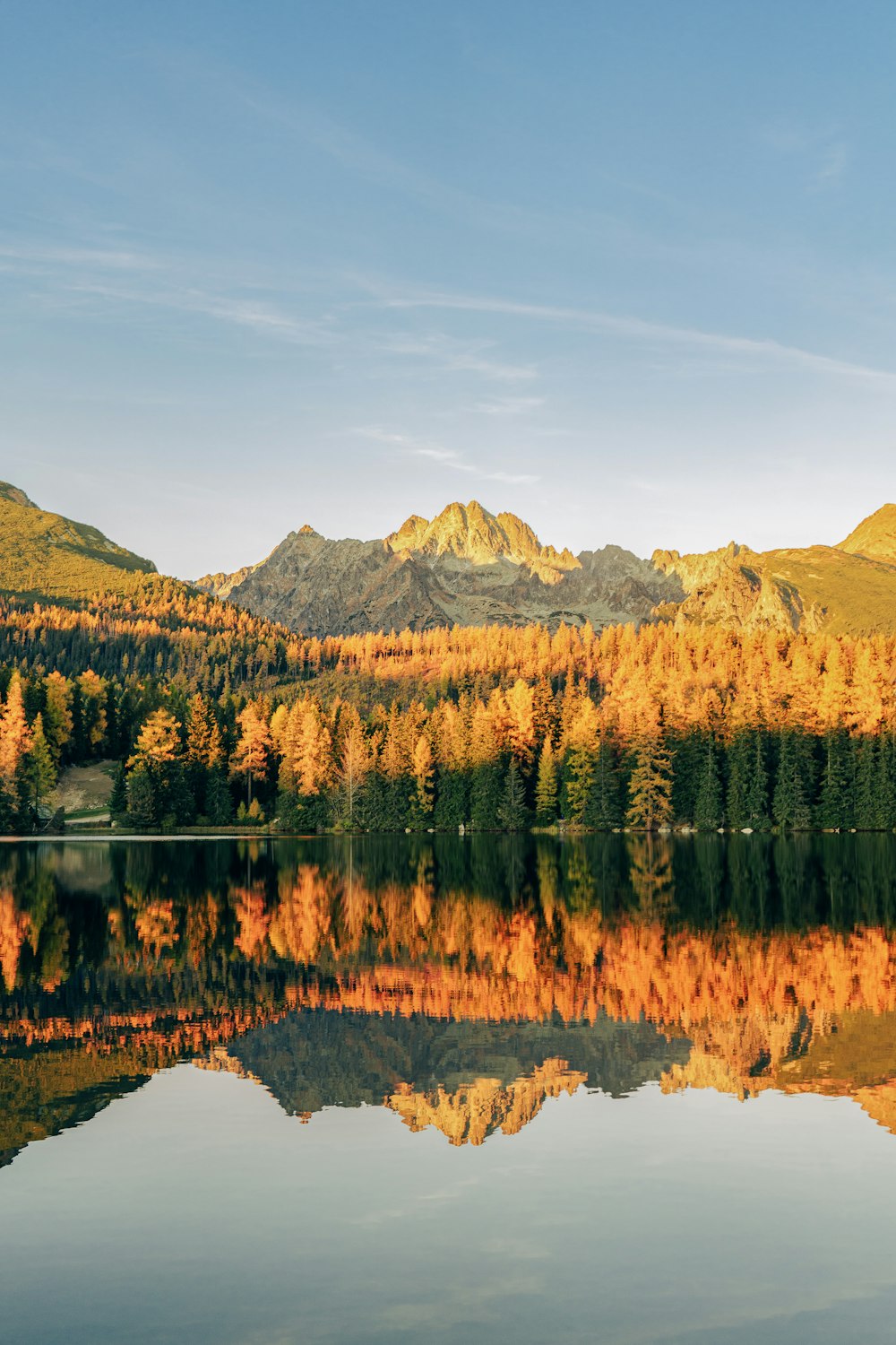 a lake surrounded by mountains with trees in the foreground