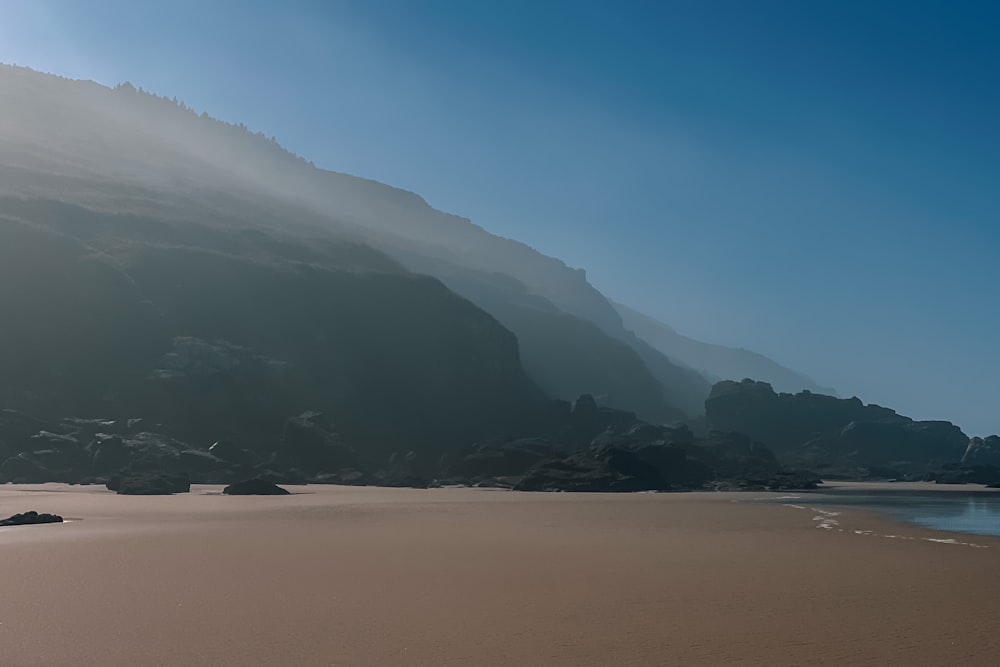 a sandy beach with a mountain in the background