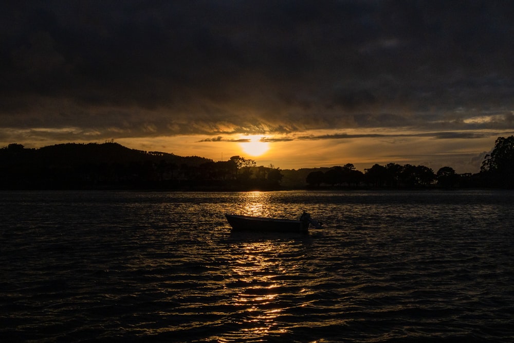 a boat floating on top of a lake under a cloudy sky