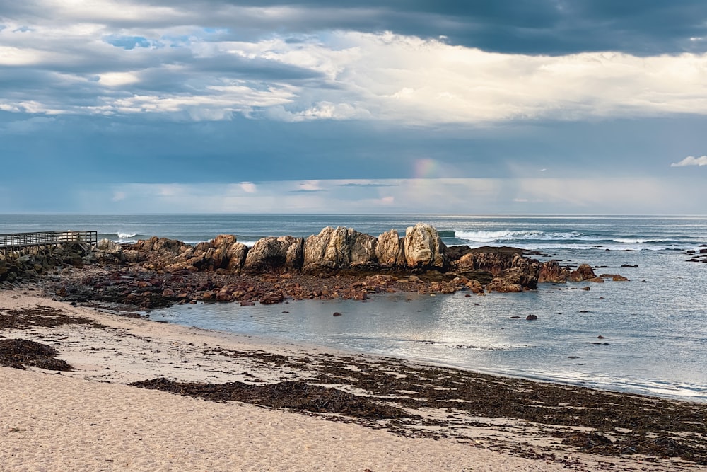 a sandy beach next to the ocean under a cloudy sky