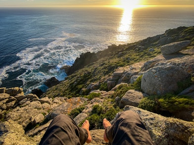 a person sitting on a cliff overlooking the ocean