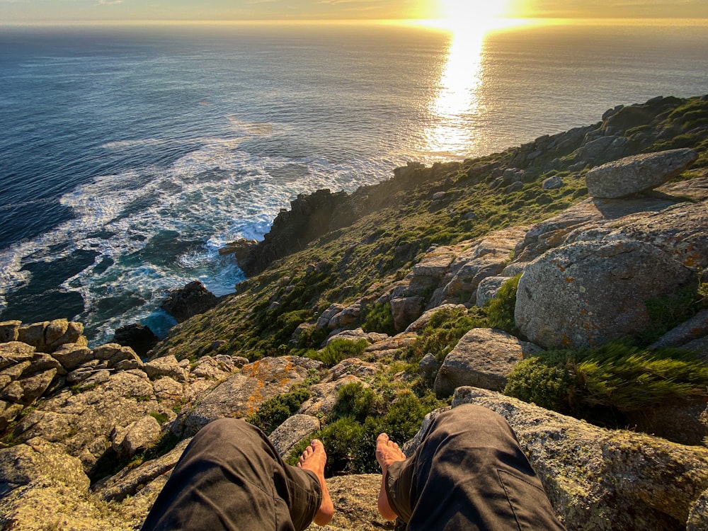 a person sitting on a cliff overlooking the ocean