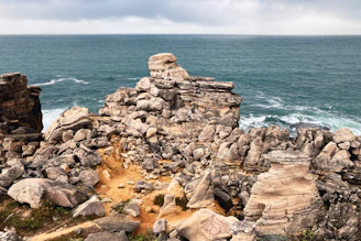 a rocky outcropping near the ocean on a cloudy day