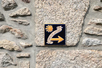 a sign on a stone wall pointing to the right