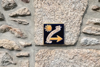 a sign on a stone wall pointing to the right