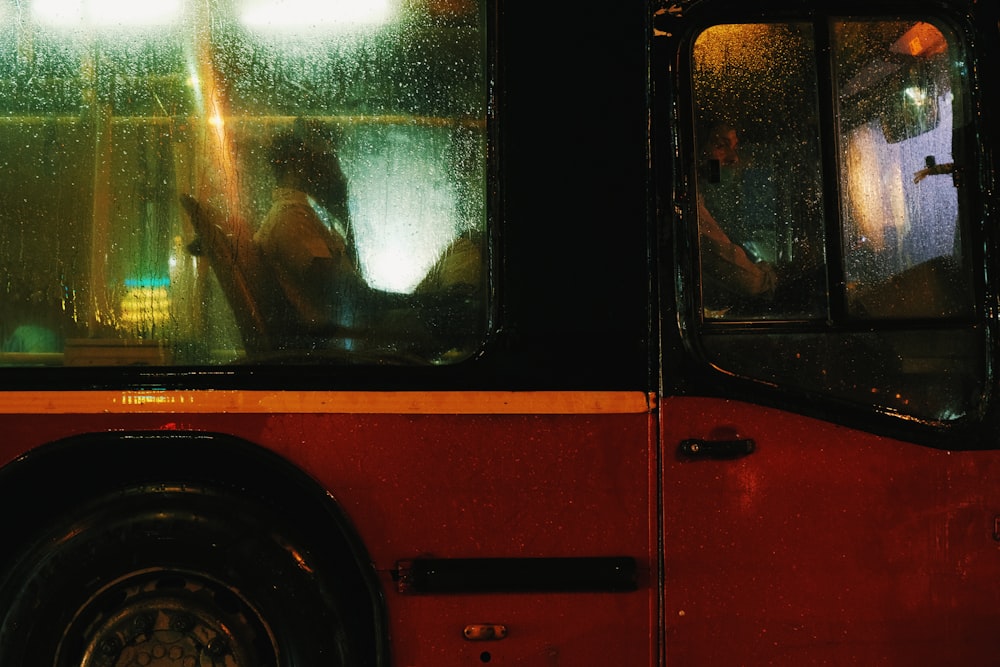 a red bus driving down a street next to a tall building