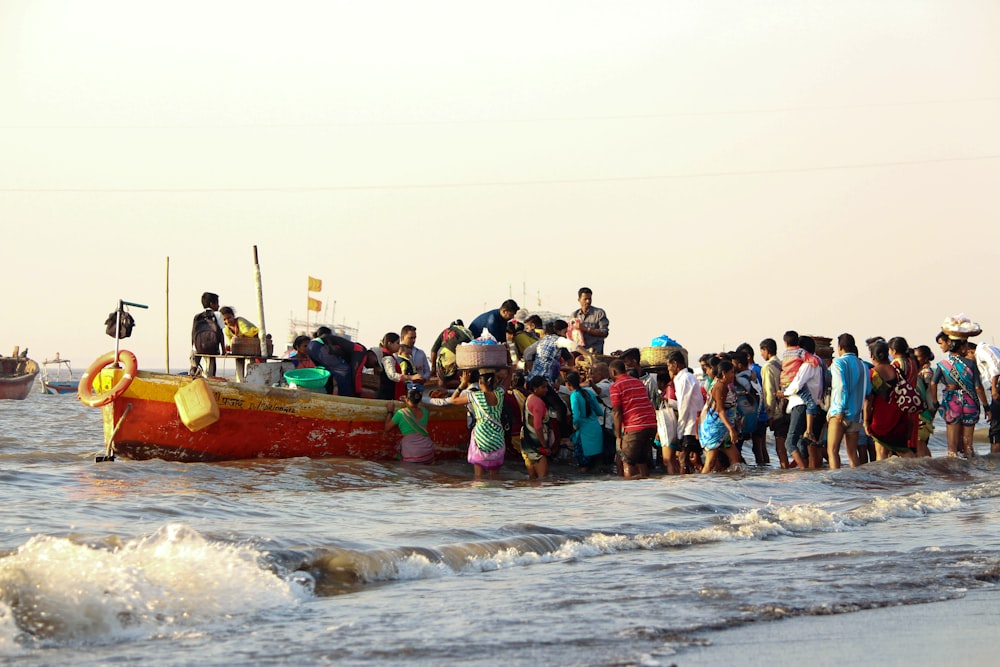 a group of people standing on a beach next to a boat