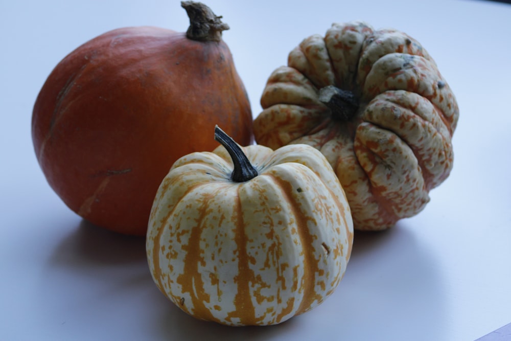 a group of three pumpkins sitting on top of a table