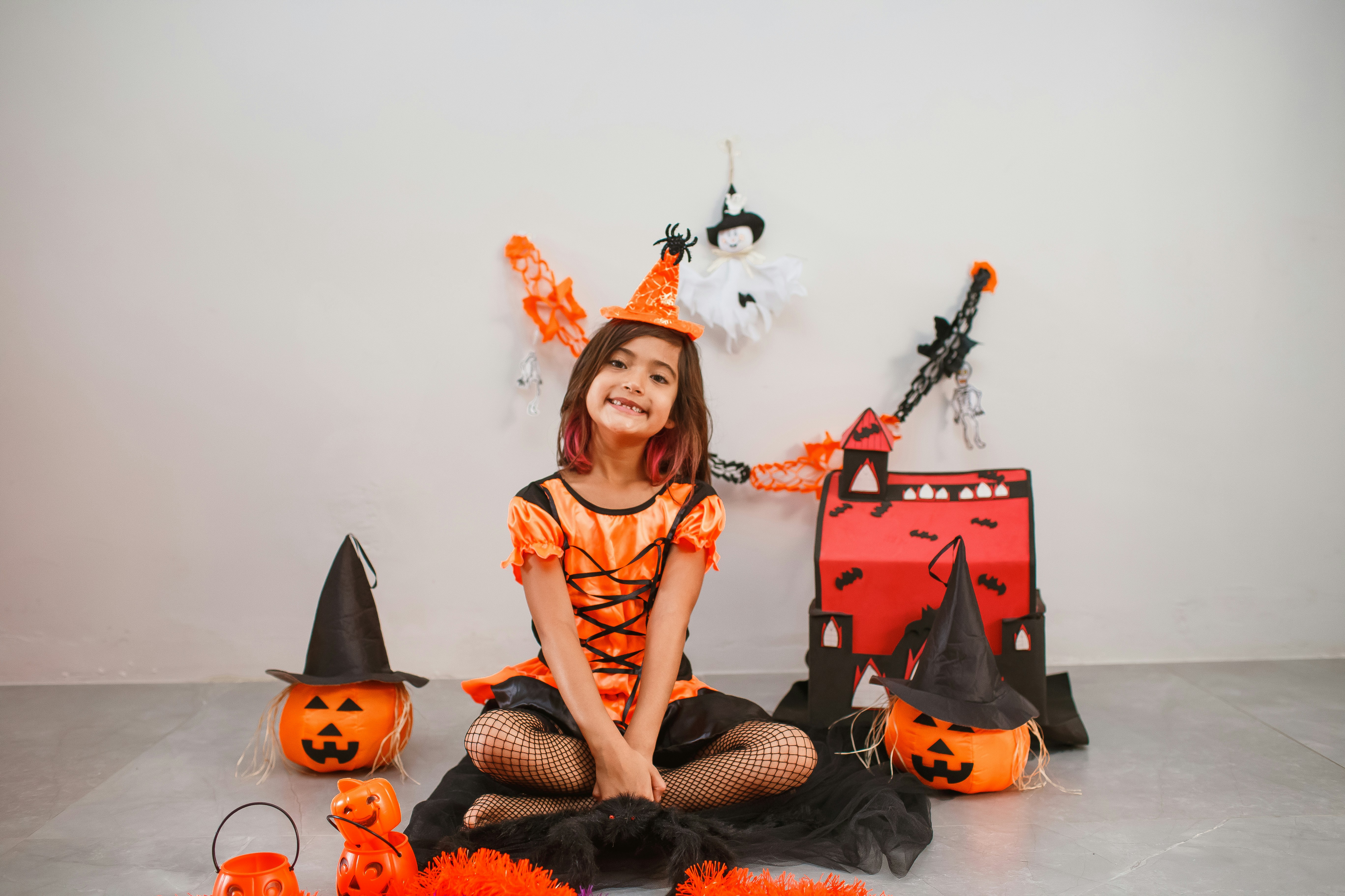 a little girl dressed up as a witch sitting on the floor