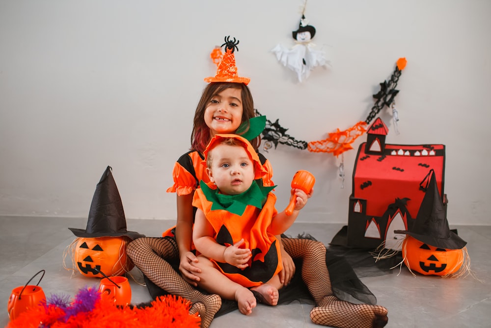 two children dressed up as witches sitting on the floor