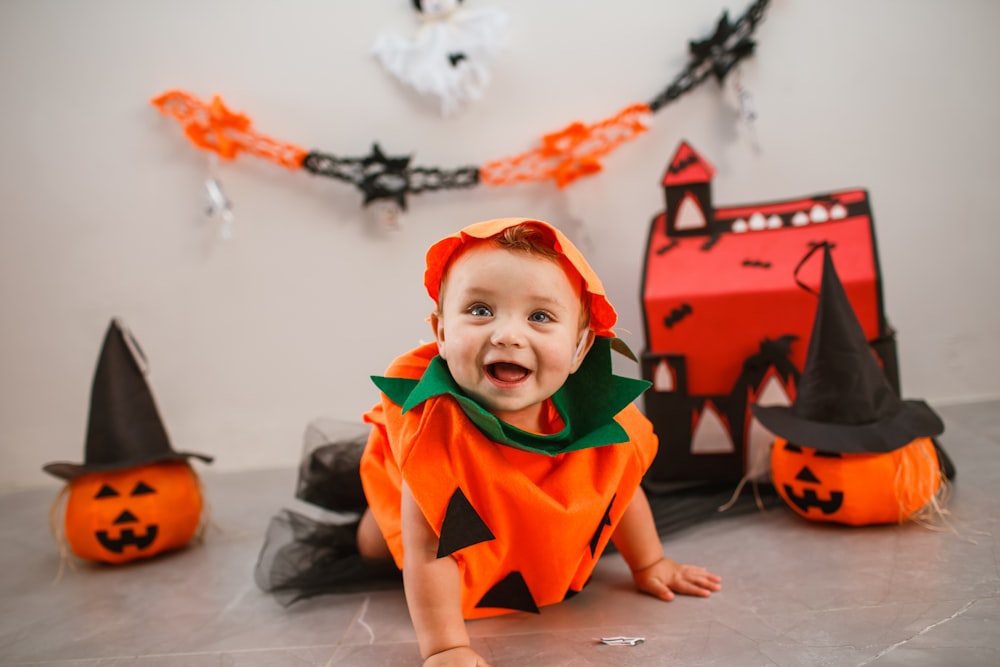 Un bambino in un costume di Halloween seduto sul pavimento
