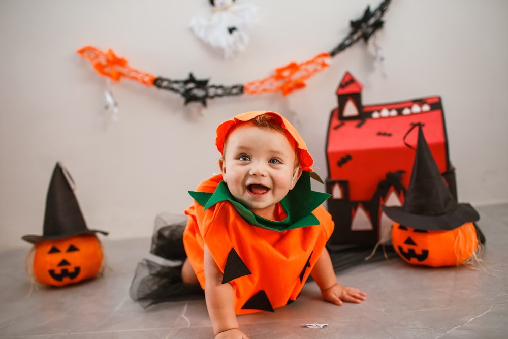 床に座っているハロウィーンの衣装を着た赤ちゃん