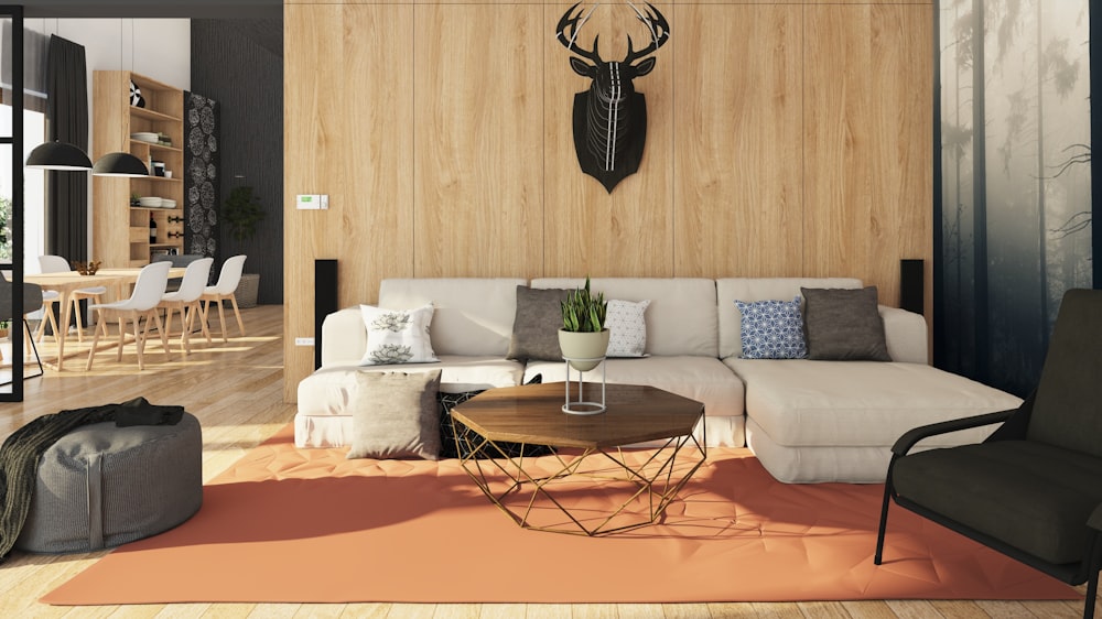 a living room with a couch, chair, table and deer head on the wall