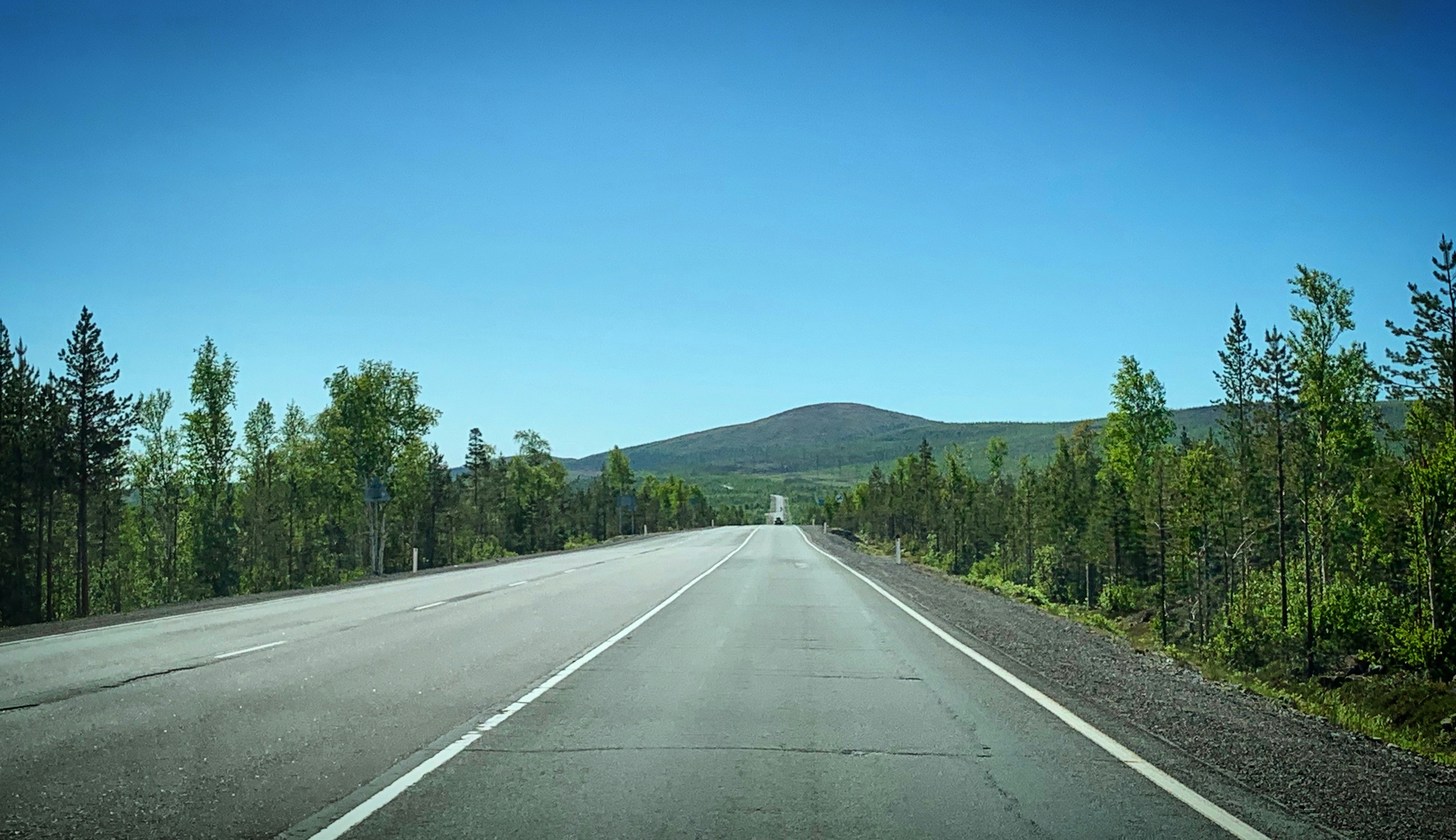 an empty highway with a mountain in the background
