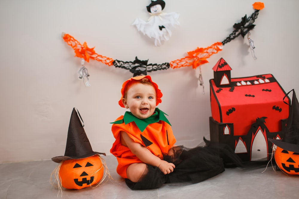 a baby in a halloween costume sitting on the floor