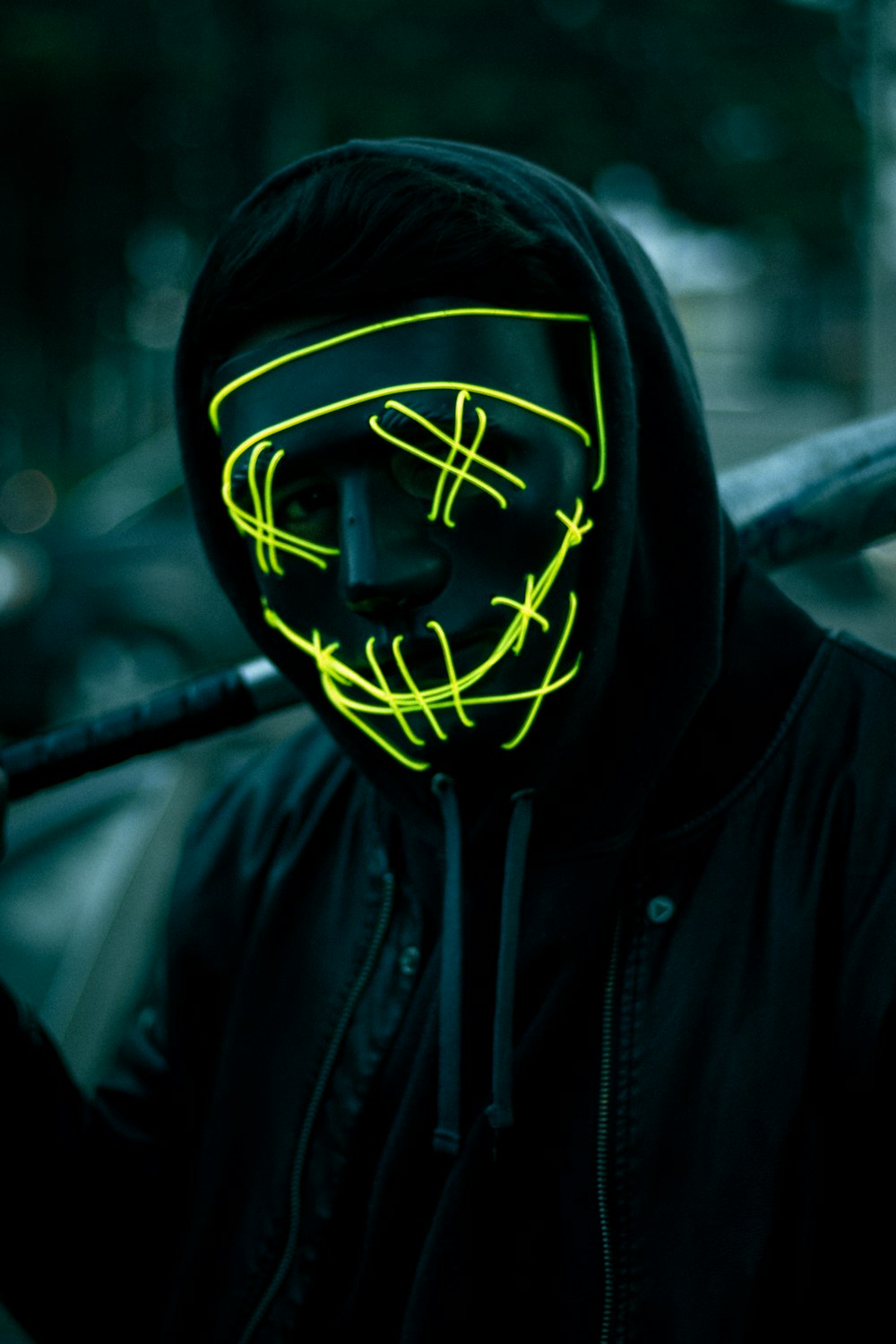 a man wearing a neon mask holding a baseball bat