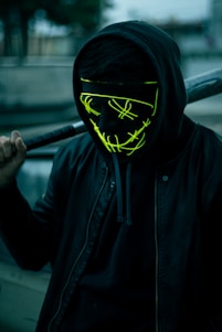 a man wearing a neon mask holding a baseball bat