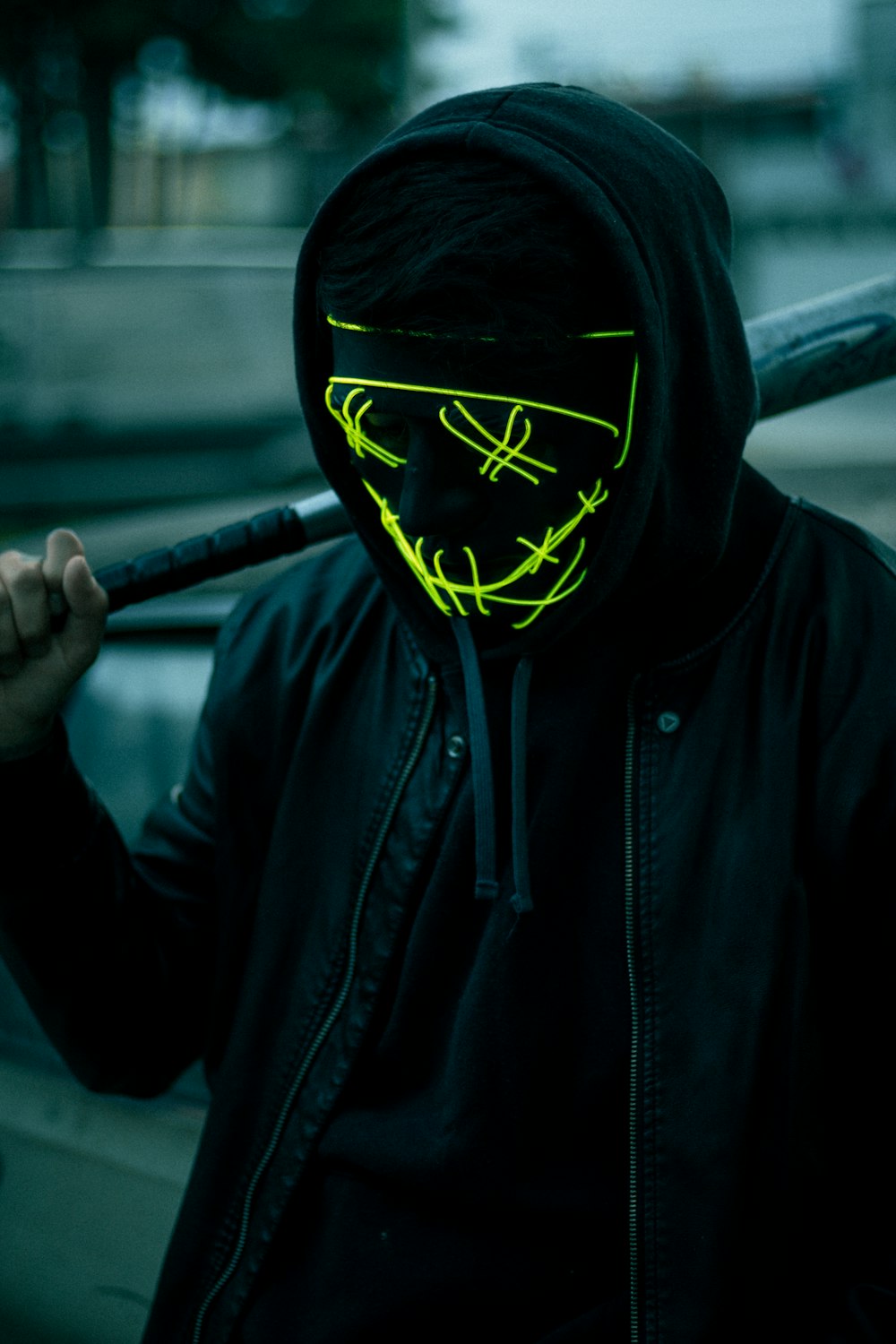 a man wearing a neon mask holding a baseball bat