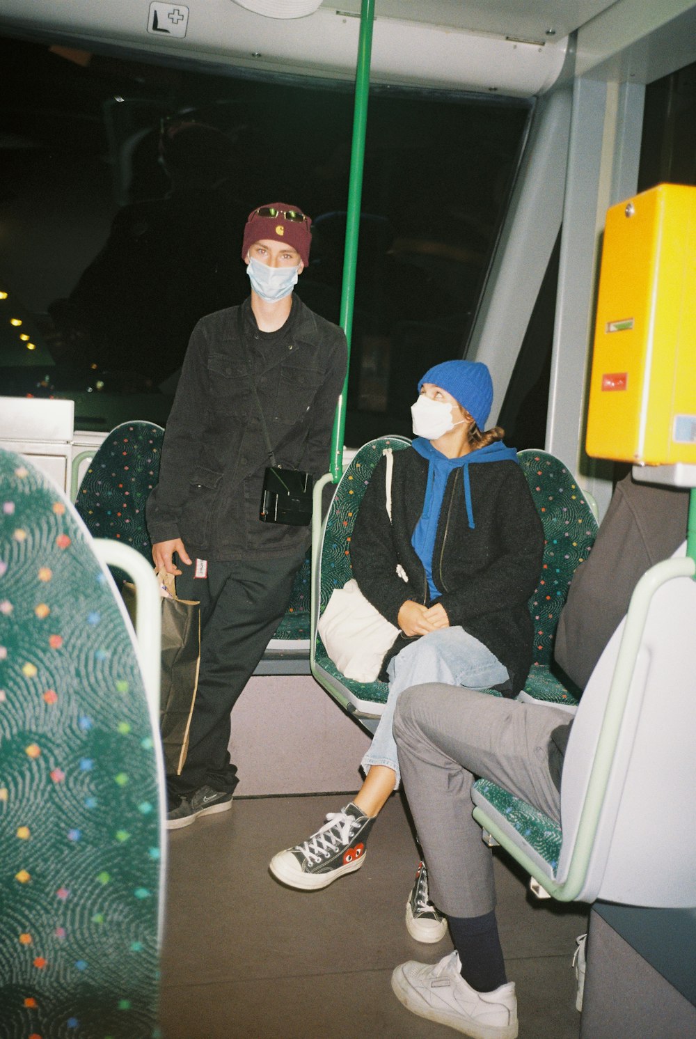 two people sitting on a bus wearing masks