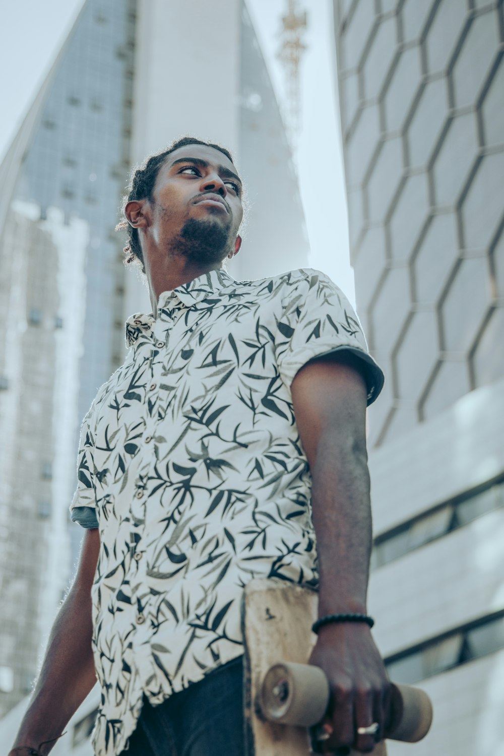 a man holding a skateboard in front of a tall building